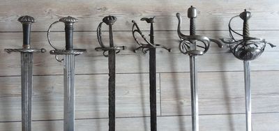 Six poignées d'épées alignées, illustrant l'évolution de l'épée de lansquenet vers la rapière