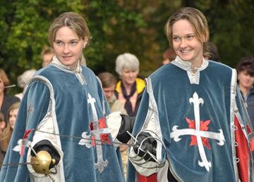 Zwei Frauen in blauen Musketier-Umhängen mit Degen